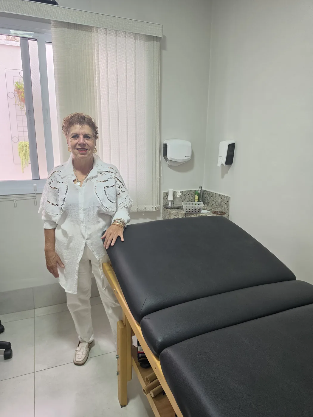 Beth Perez ao lado da maca no consultório