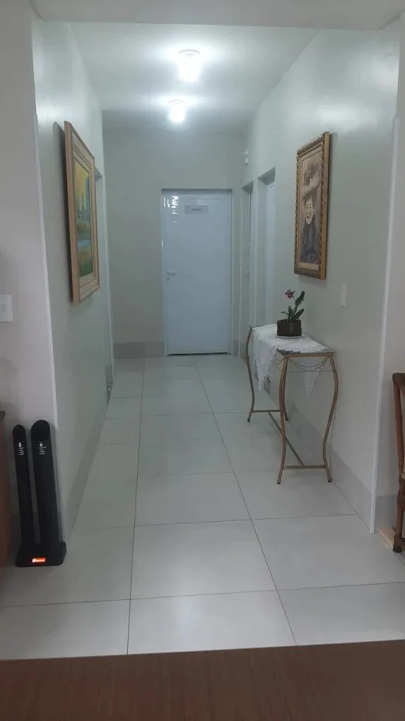 Corredor claro do centro terapêutico com quadros e aparador